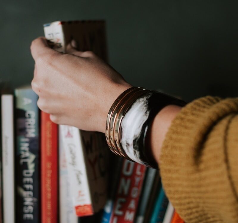 Illustratives Bild einer Hand, die ein Buch aus dem Bücherregal greift