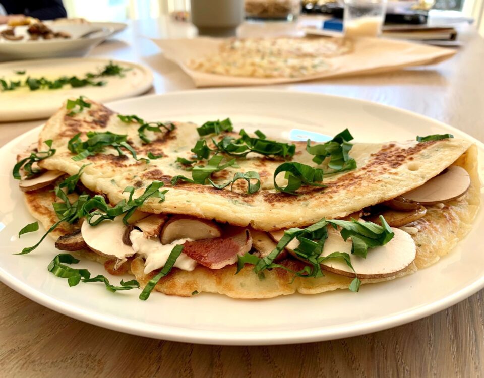 Bild eines zusammengeklappten Pfannkuchens mit Pilzen auf einem Teller