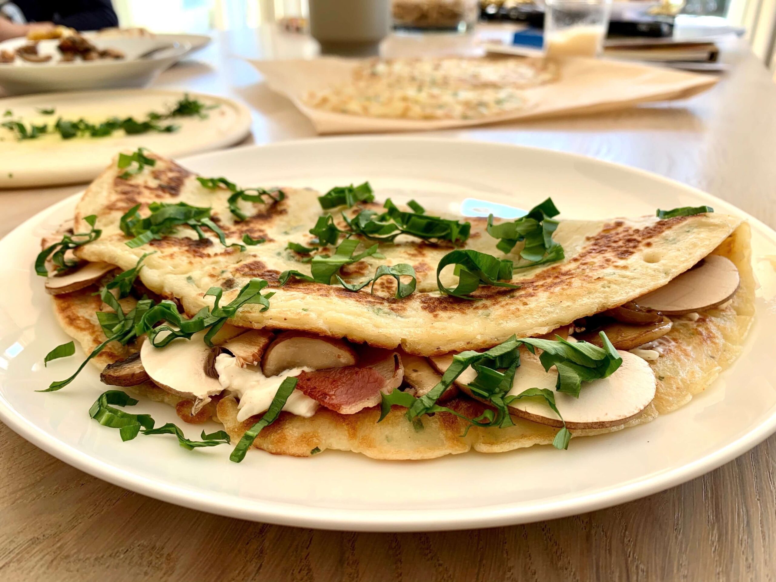 Bild eines zusammengeklappten Pfannkuchens mit Pilzen auf einem Teller