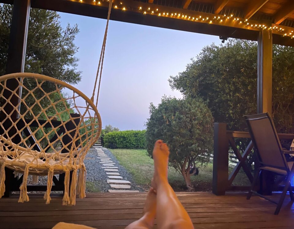 Blick von einer Terrasse auf den Garten mit hochgelegten Beinen