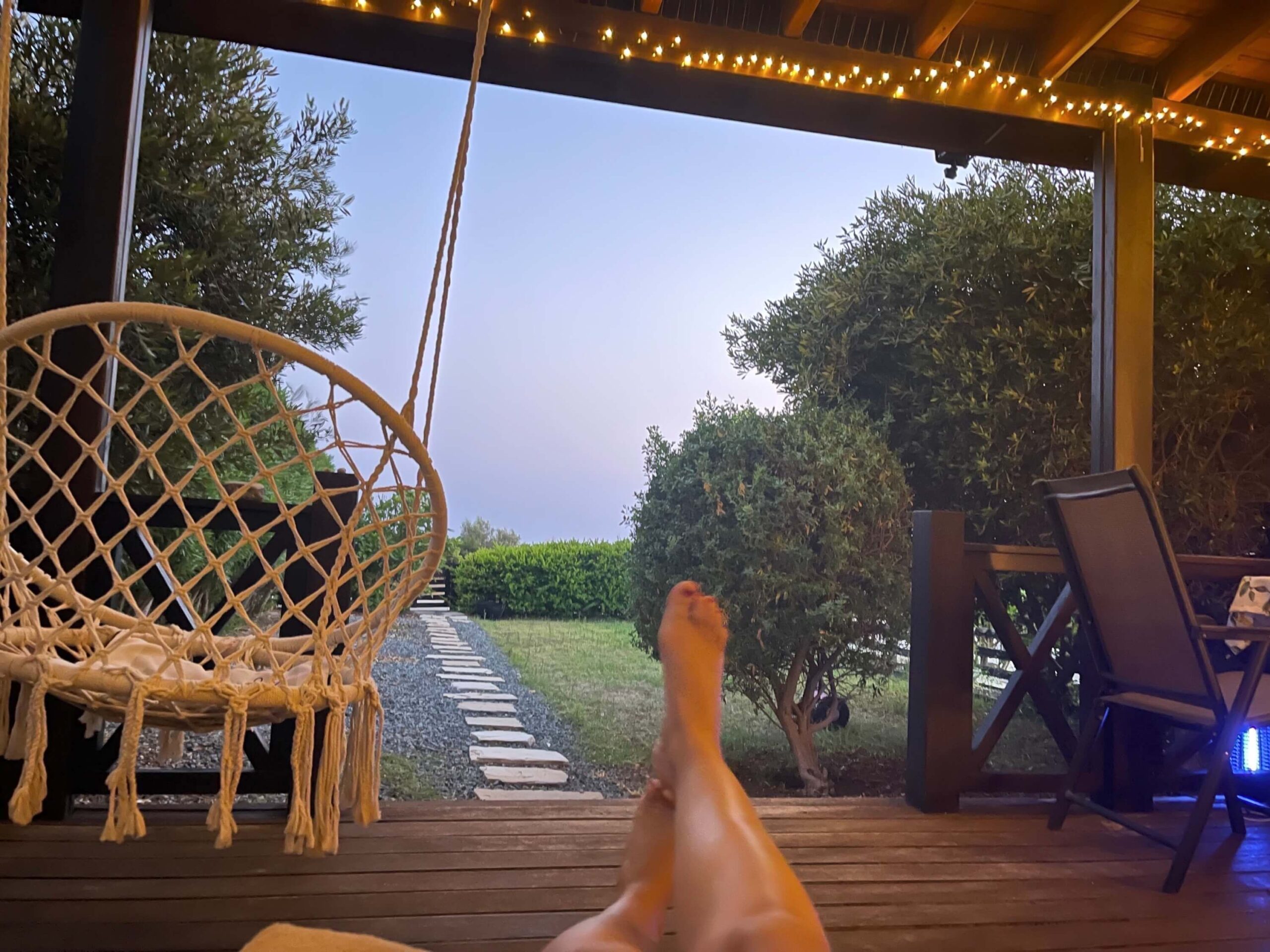 Blick von einer Terrasse auf den Garten mit hochgelegten Beinen