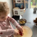 Kind schneidet Gemüse in der Küche